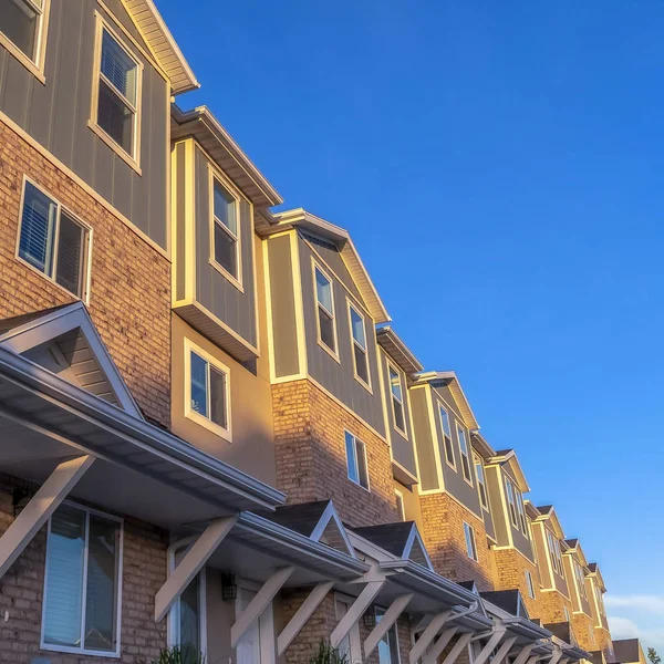 Négyzet alakú keret Külső lakóházak néző élénk kék ég és a hó sapkás hegy — Stock Fotó
