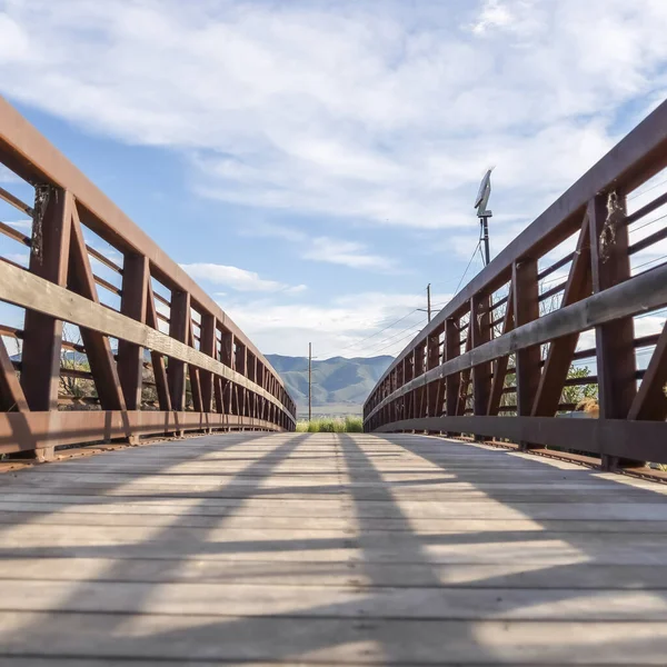 Marco cuadrado Enfoque en puente con rejilla marrón barandilla de metal y cubierta de madera iluminada por el sol —  Fotos de Stock