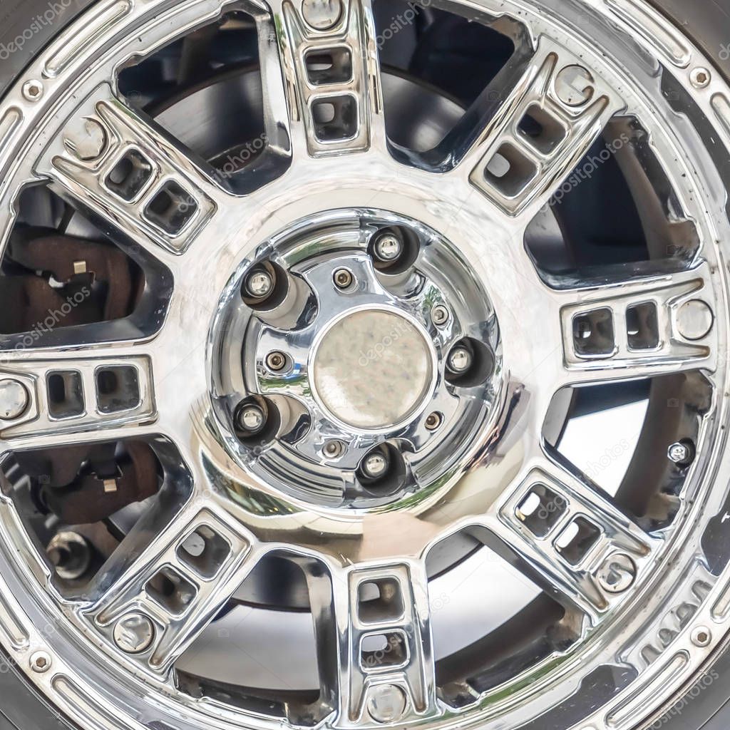 Square Close up of the black rubber tire of an off roading truck with shiny chrome mags