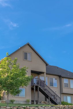 Güneşli bir günde canlı mavi gökyüzüne karşı gable ve vadi çatısı olan bir ev.