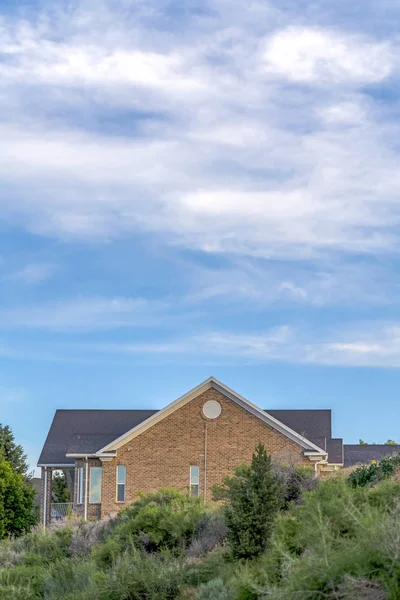 Cielo azul y nubes sobre una casa con techo gris y pared exterior de ladrillo — Foto de Stock