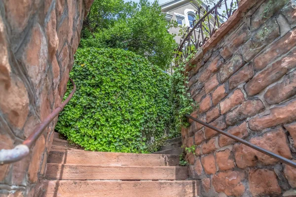 Close up of outdoor stairs amid stone brick retaining walls that leads to a home