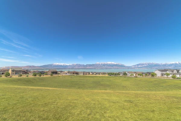 Campo de golf cubierto con hierbas verdes vibrantes con vistas a las casas y el lago —  Fotos de Stock