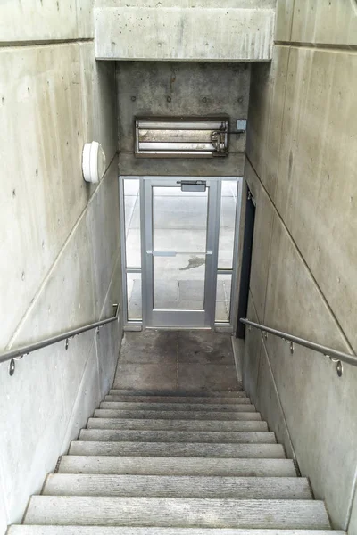 Escadaria dentro de um edifício descendo para uma porta de vidro que leva ao ar livre — Fotografia de Stock