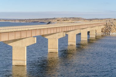 Sakin göle yayılan Stringer köprüsü karlı arazi ve bulutlu gökyüzü manzaralı