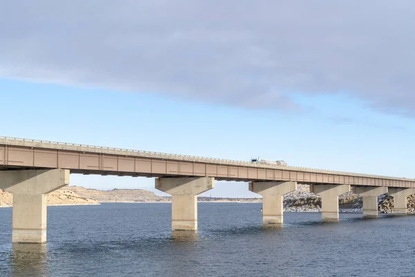Stringer bridge supported by abutments ovelooking lake land and cloudy sky — 스톡 사진