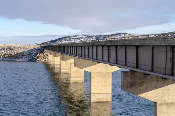 View of the abutments underneath a beam bridge supporting the deck over lake