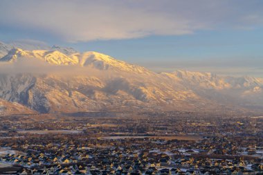 Timpanogos Dağı ve kışın taze karla kaplı evler gün batımında aydınlanıyor.