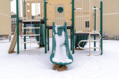 Çocukların oyun parkında kışın karla kaplı zemine karşı yeşil slaytlar