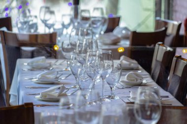 Şarap kadehleri ve sofra takımı sosyal bir toplantı için bir masaya dizilmiştir.