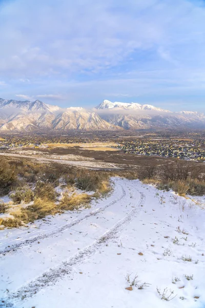 Camino de tierra en terreno montañoso con residencias y vista al monte Timpanogos en invierno —  Fotos de Stock