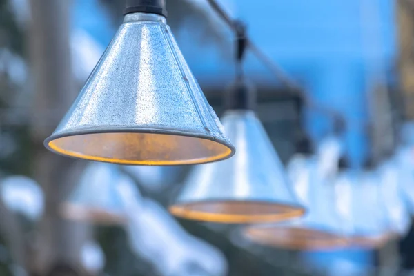 Dekorative kegelförmige Lampen, die im Winter vor dem Haus an schwarzen Schnüren hängen — Stockfoto