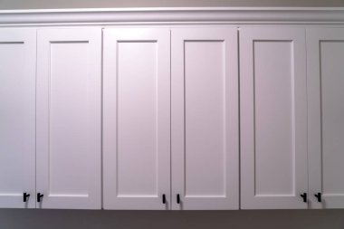 Evin duvarına asılmış siyah saplı beyaz ahşap dolaplar.