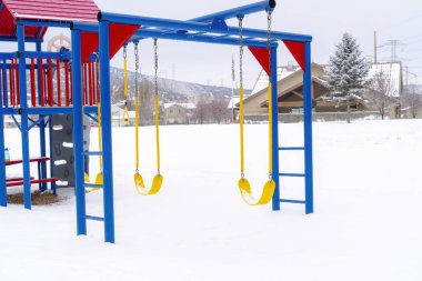 Beyaz kara karşı canlı salıncaklar ve maymun barı kış manzarasını kapladı.