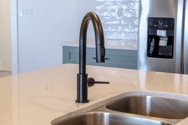 Ev mutfak adasında siyah musluk ve paslanmaz çelik çift lavabo.