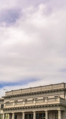 Dikey çerçeve Bulutlu mavi gökyüzü balkonlu ve girişteki büyük sütunlu bina