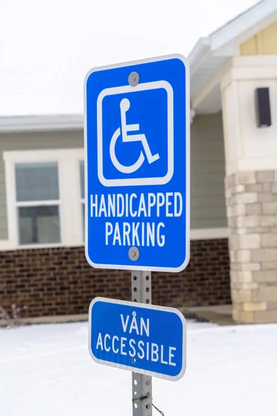 Handicapped Parking and Van Accessible sign against snow and building in winter
