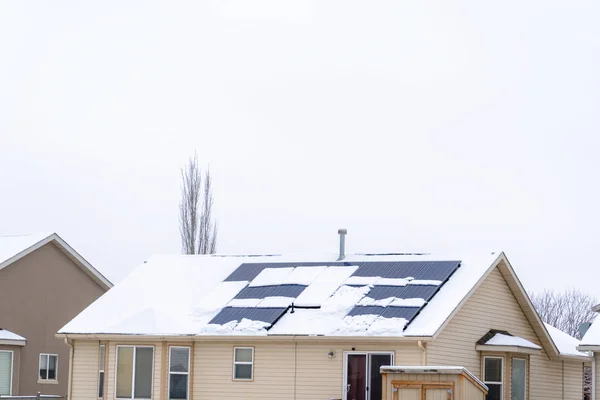 Telhado coberto de neve de casa com painéis solares contra céu nublado no inverno — Fotografia de Stock