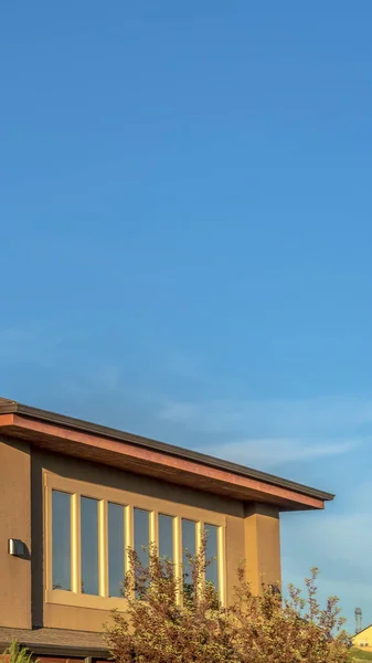 Vertical Planta superior de una casa con pared marrón forrada de ventanas contra el vasto cielo azul — Foto de Stock