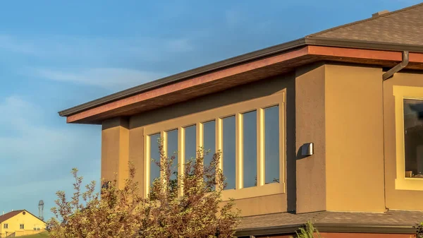 Marco panorámico Planta superior de una casa con pared marrón forrada de ventanas contra el vasto cielo azul — Foto de Stock
