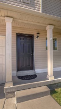 Dikey çerçeve beton verandalı ve garaj kapısının yanındaki ön kapılı ev cephesi