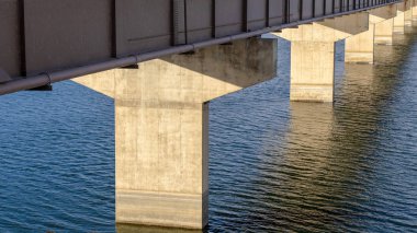 Bir kiriş köprüsünün panorama güvertesi mavi su üzerinde uzanan katman ya da rıhtımlar tarafından destekleniyor