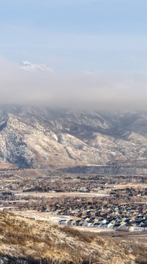 Banliyödeki evler, karla kaplı, çarpıcı dağ manzaralarıyla çevrili.