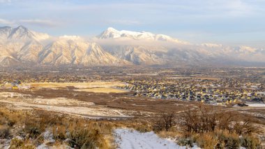 Fotoğraf Panorama çerçeveli tepedeki karlı toprak yol mahalle evleri ve Timpanogos Dağı manzaralı