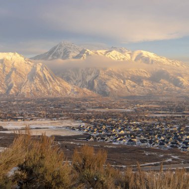Kışın tepemizde bulutlu mavi gökyüzü olan Timpanogos Dağı 'nın altındaki kare evler