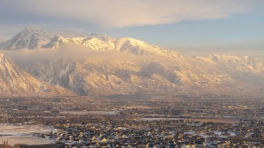 Panorama çerçevesi kışın üzerinde bulutlu mavi gökyüzü olan Timpanogos Dağı 'nın altındaki evler