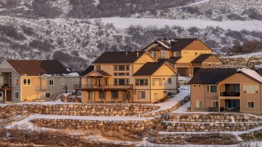 Fotoğraf Panorama Günbatımı, kışın karla kaplı mahalledeki evleri aydınlatıyor.