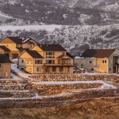 Fotoğraf meydanı çerçevesi kışın karla örtülü mahalledeki evleri aydınlatan gün batımı.