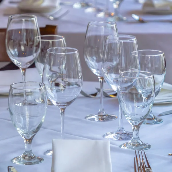 Photo Square frame Wine glasses spoons forks saucer plates and napkins on a table with white cloth