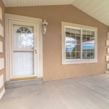 Kare çerçeve sundurma beyaz ön kapı, ev girişinde cam camlar ve pencereler var.