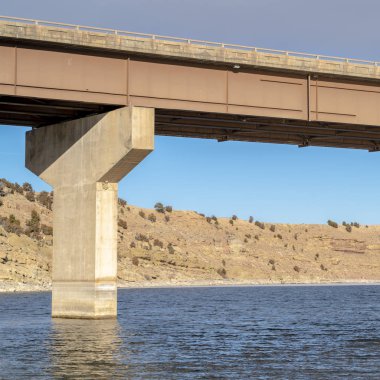 Kare çerçeve kiriş köprüsü engebeli kara ve bulutlu gökyüzüne karşı ayaklanma temeli ile