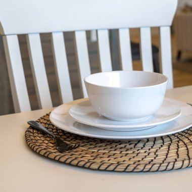 Kare çerçeve yemek masası seti kase tabakları tabak altlığı ve tahta sandalye.