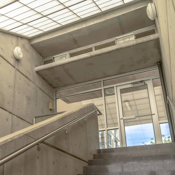 Quadro quadrado escadas de concreto com paredes laterais e corrimãos sob inclinação telhado de vidro inclinado — Fotografia de Stock