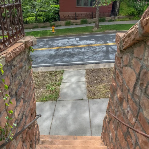 Square Outdoor stairs between retaining walls made of stone leading to a sunlit road