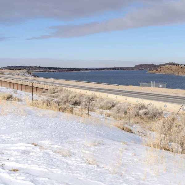 Square Snow covered terrain along a road overlooking mountain and lake in winter — Stock Photo, Image