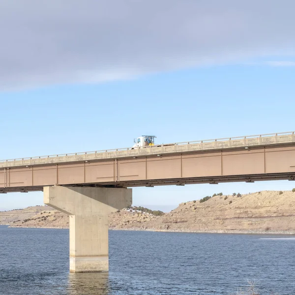 Square frame Bridge across a lake with scenic view of hills and cloudy blue sky in winter — 스톡 사진