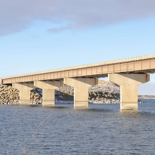 Square frame Stringer bridge crossing over a blue lake and connecting snowy rocky terrains — 스톡 사진