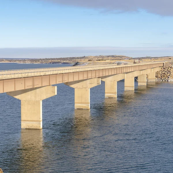 Square Blue meer met brug verbinden uitgestrekte terreinen bedekt met sneeuw in de winter — Stockfoto