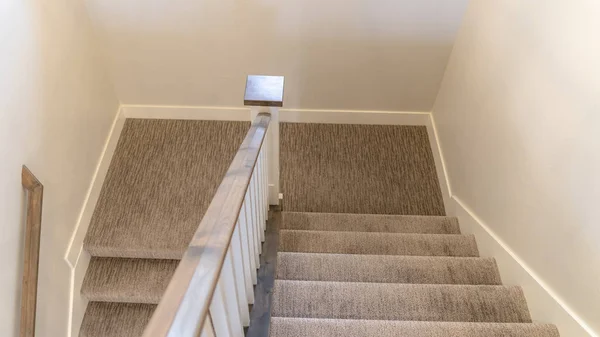 Foto Panorama Escalera en forma de U con pasamanos y alfombra gris dentro de una casa con pared blanca —  Fotos de Stock