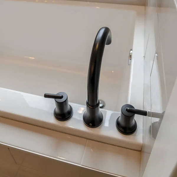 Photo Square frame Matte black faucet and handles on a glossy clean white built in bathtub — 스톡 사진