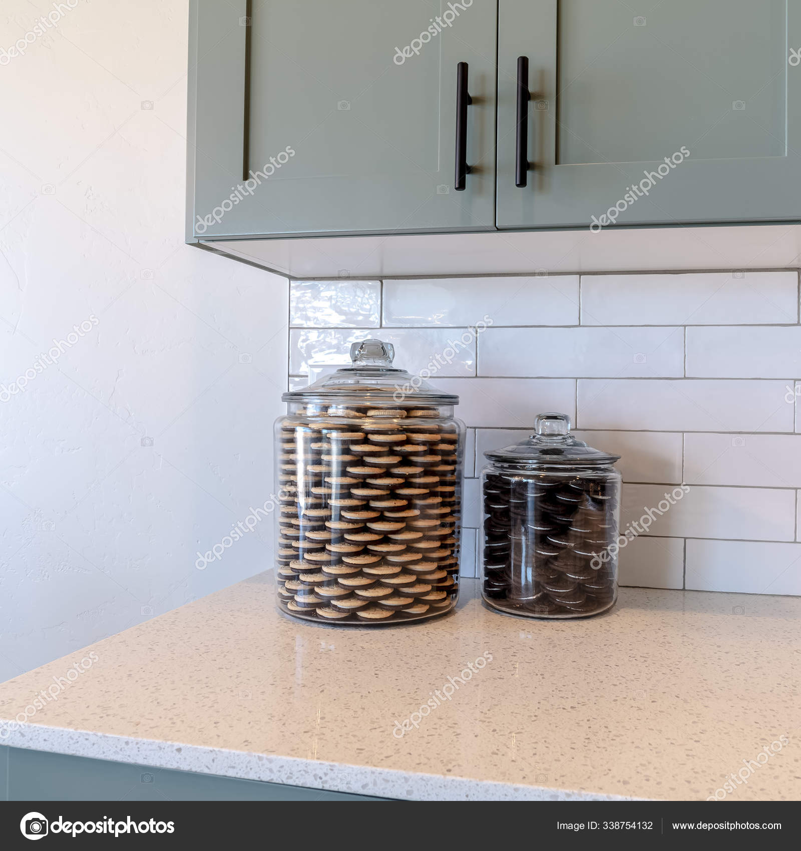 Square Jars of cookies on kitchen counter top against tile