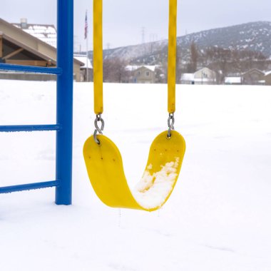 Fotoğraf Meydanı çerçevesi kışın beyaz kara karşı renkli oyun parkında canlı sarı salıncaklar