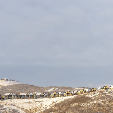 Fotoğraflı kare çerçeveli evler kışın karlı tepelerin tepesinde yuva yapmış.