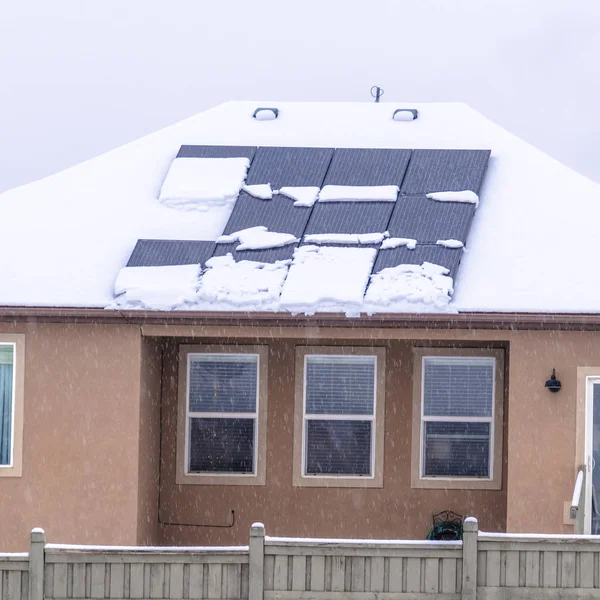 Foto Quadrado Fachada de casa com painéis solares no telhado nevado contra o céu nublado no inverno — Fotografia de Stock