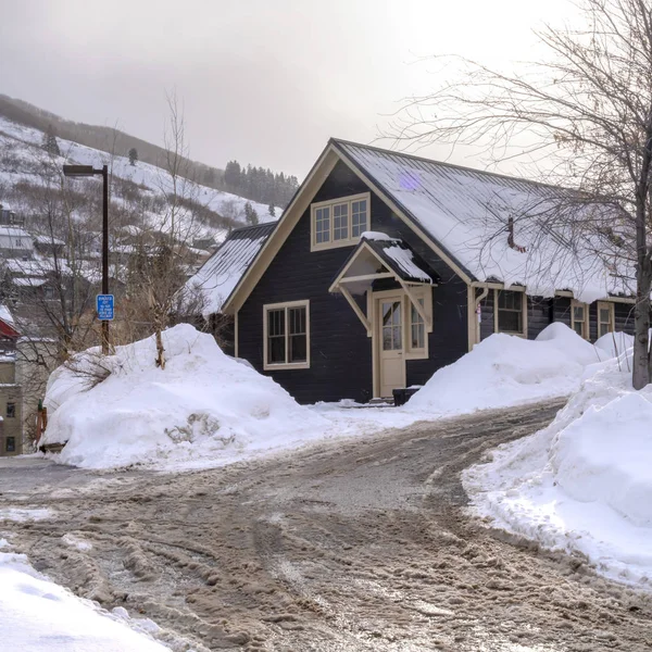 Quadratische Rahmenstraße mit schmutzigem Schnee gegen vereiste Häuser und verschneite Hügel an einem kalten Wintertag — Stockfoto