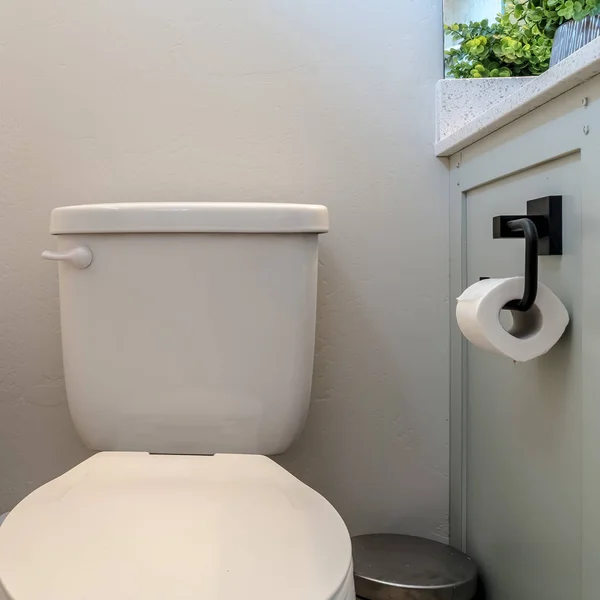 Foto quadro quadrado lata de lixo sanitário e armário com suporte de tecido contra a parede branca do banheiro — Fotografia de Stock